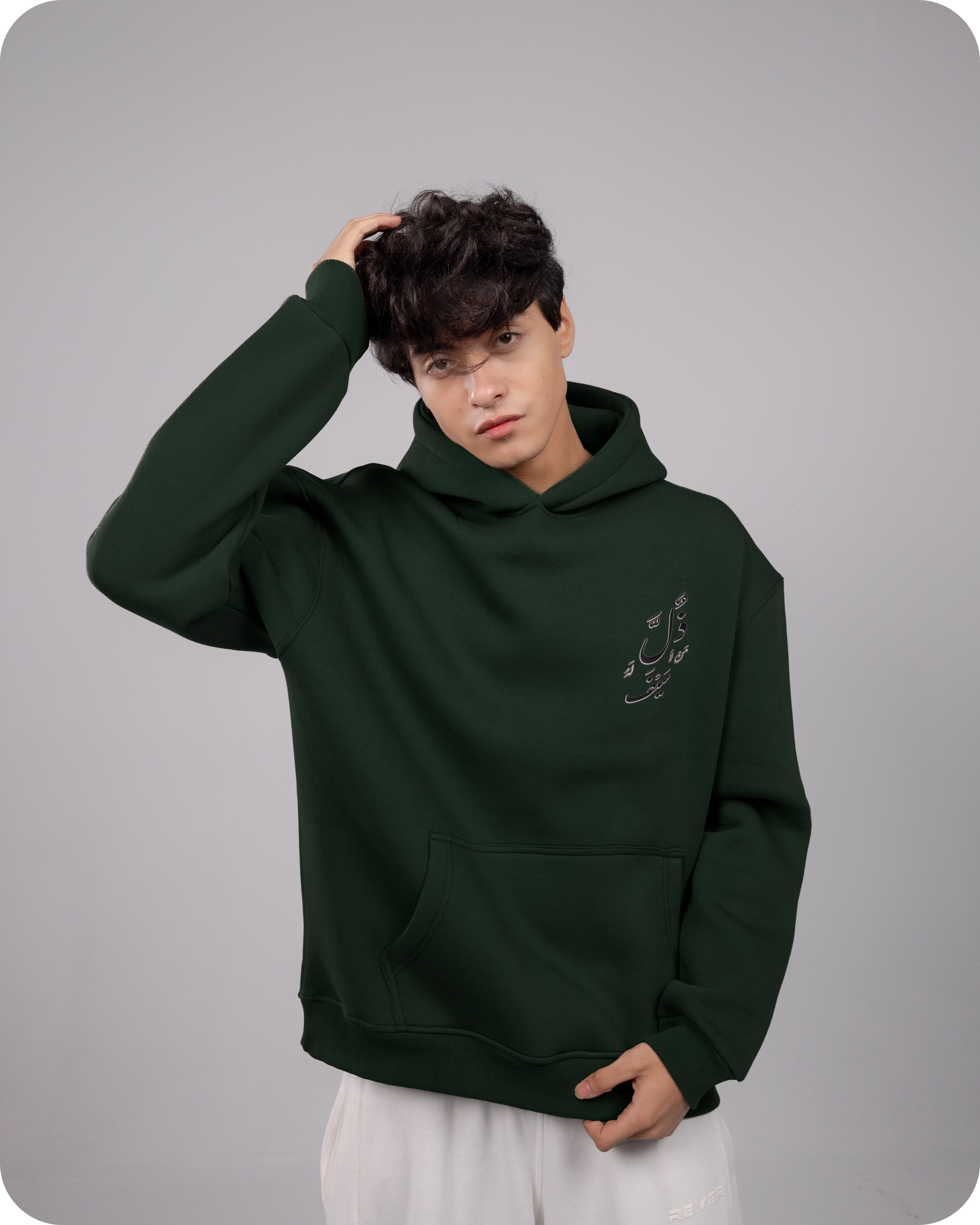 Person wearing a dark green hoodie with a small design on a gray background
