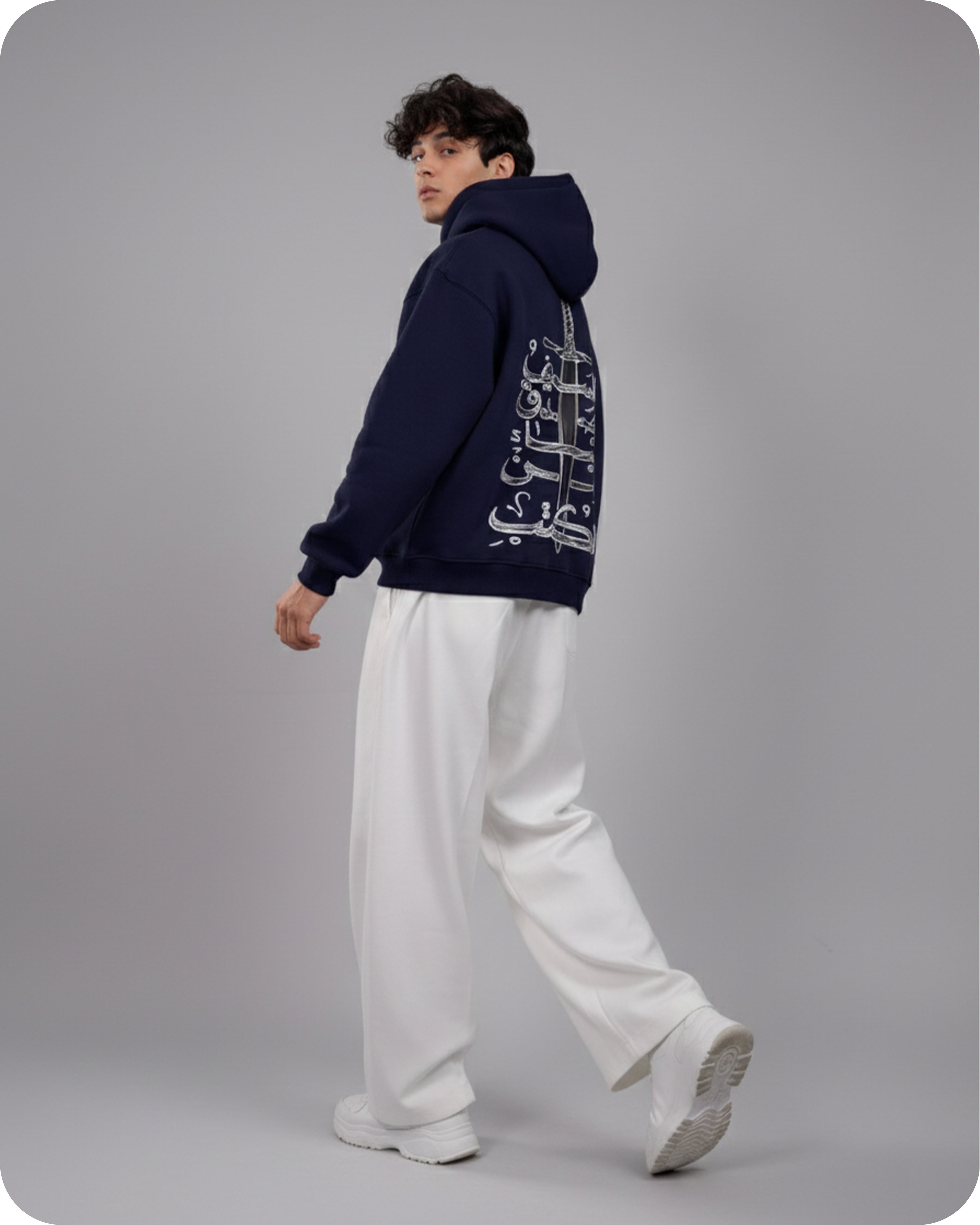 Person wearing a navy hoodie with text on the back against a gray background