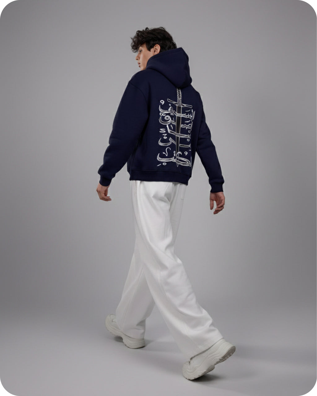 Person wearing a navy hoodie with white text on the back, standing against a gray background