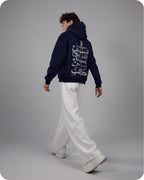 Person wearing a navy hoodie with white text on the back, standing against a gray background