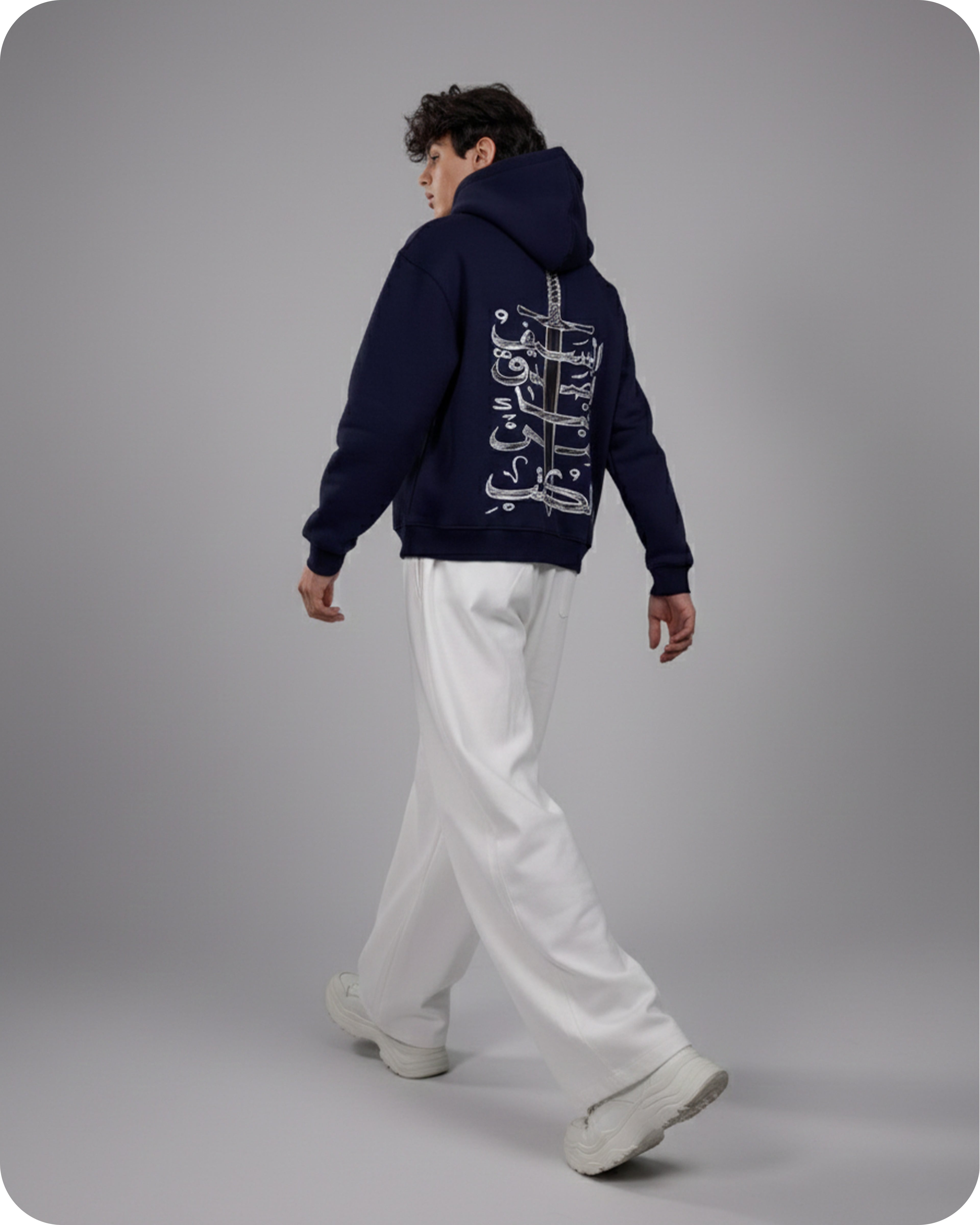 Person wearing a navy hoodie with white text on the back, standing against a gray background