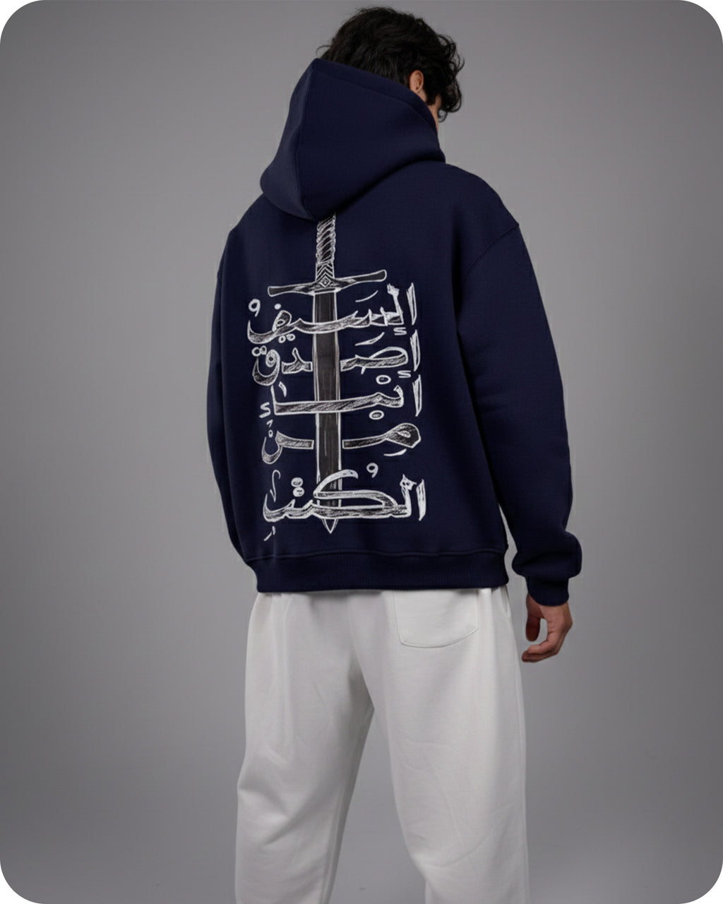Person wearing a navy hoodie with a design on the back against a gray background