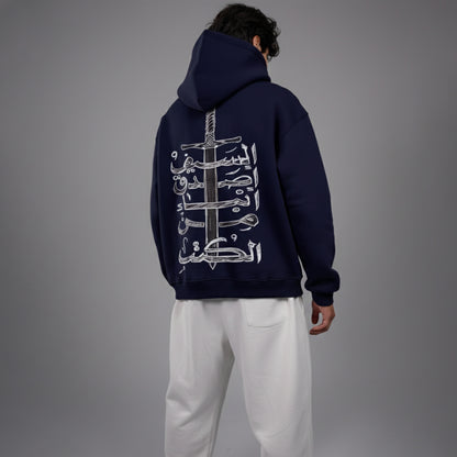 Person wearing a navy hoodie with a design on the back against a gray background