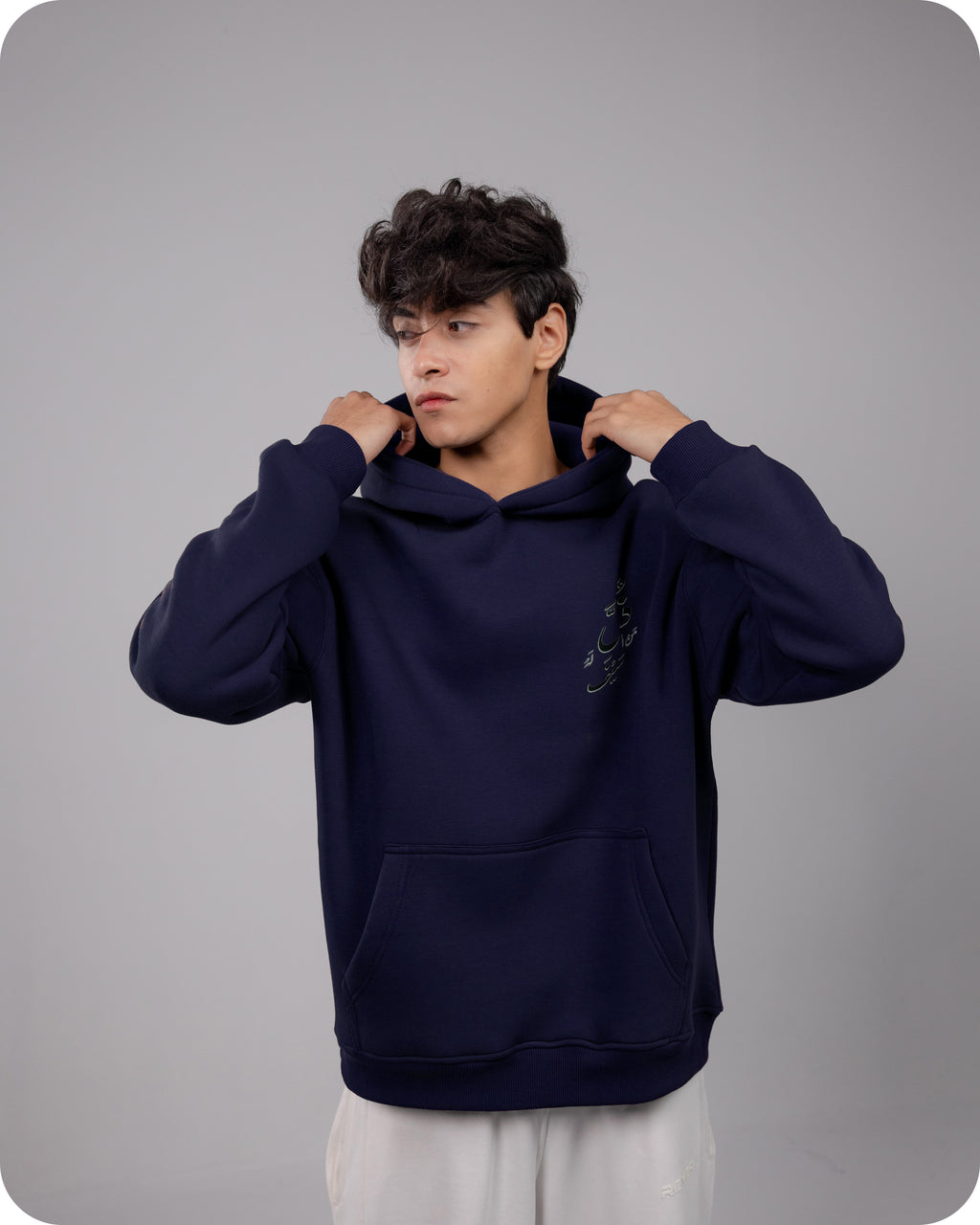 Person wearing a navy blue hoodie against a gray background