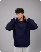 Person wearing a navy blue hoodie against a gray background