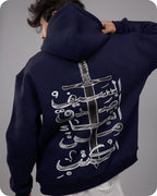 Navy hoodie with white Arabic calligraphy design on the back, worn by a person against a gray background.