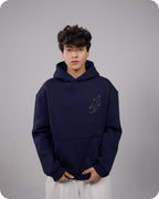 Person wearing a navy blue hoodie with a logo on a gray background