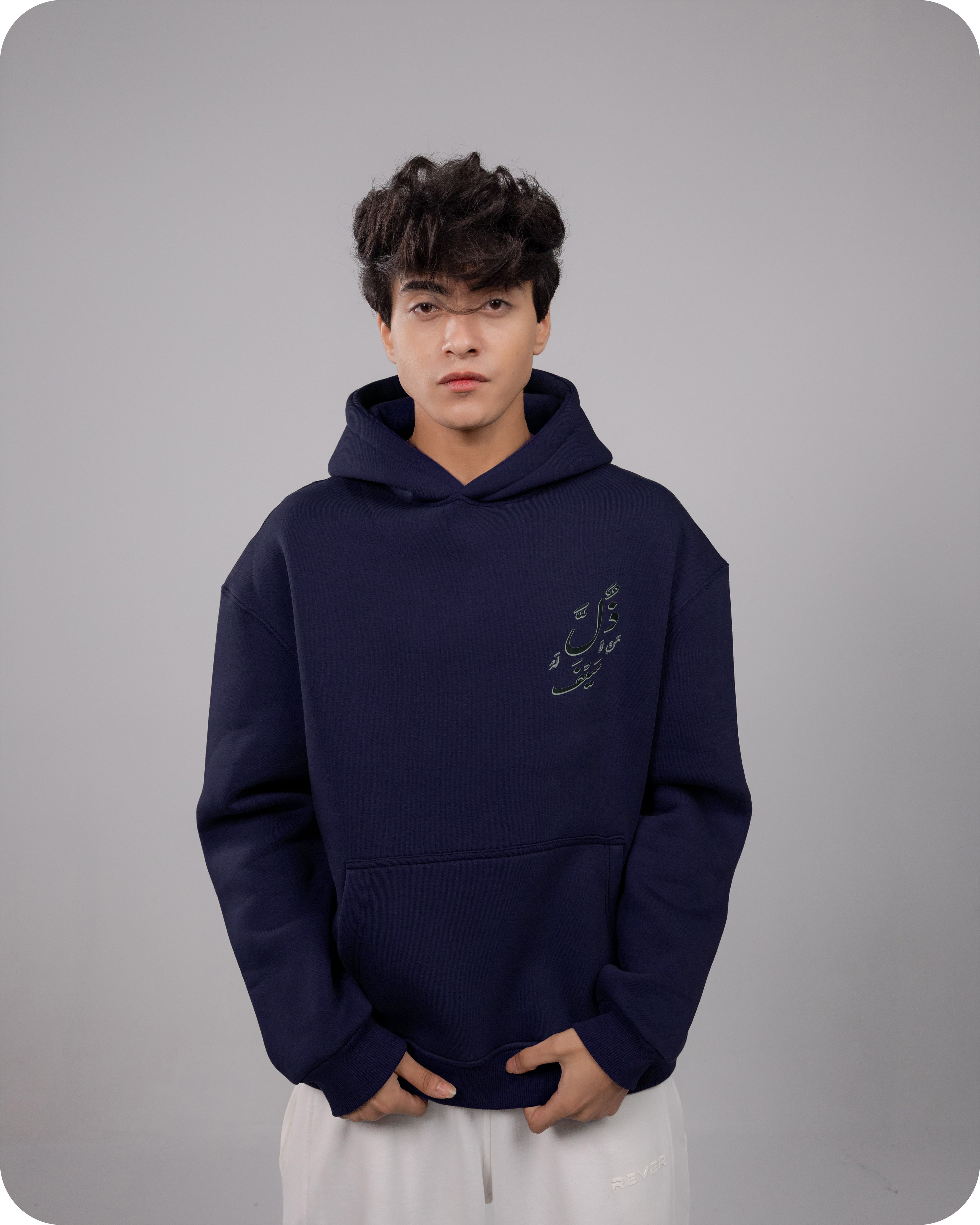 Person wearing a navy blue hoodie with a logo on a gray background