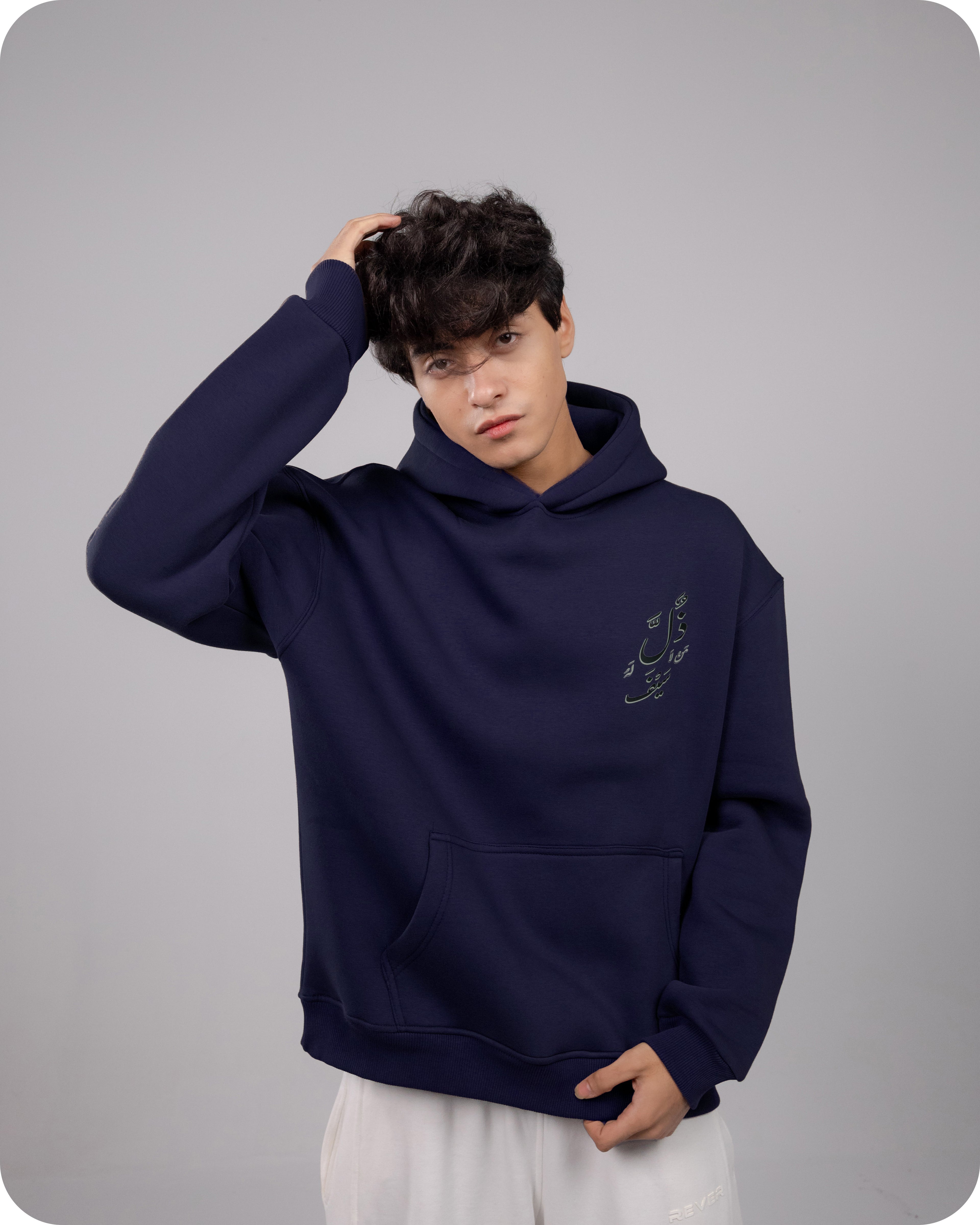 Person wearing a navy blue hoodie with a small design on a gray background