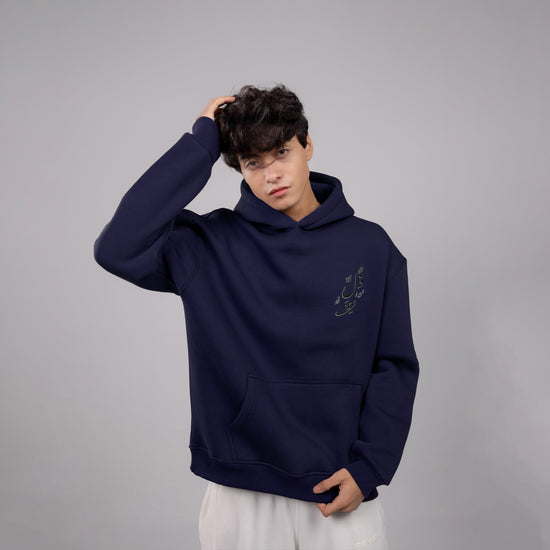 Person wearing a navy blue hoodie with a small design on a gray background
