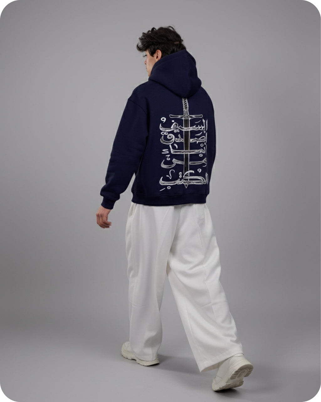 Person wearing a navy hoodie with white text on the back, standing against a gray background