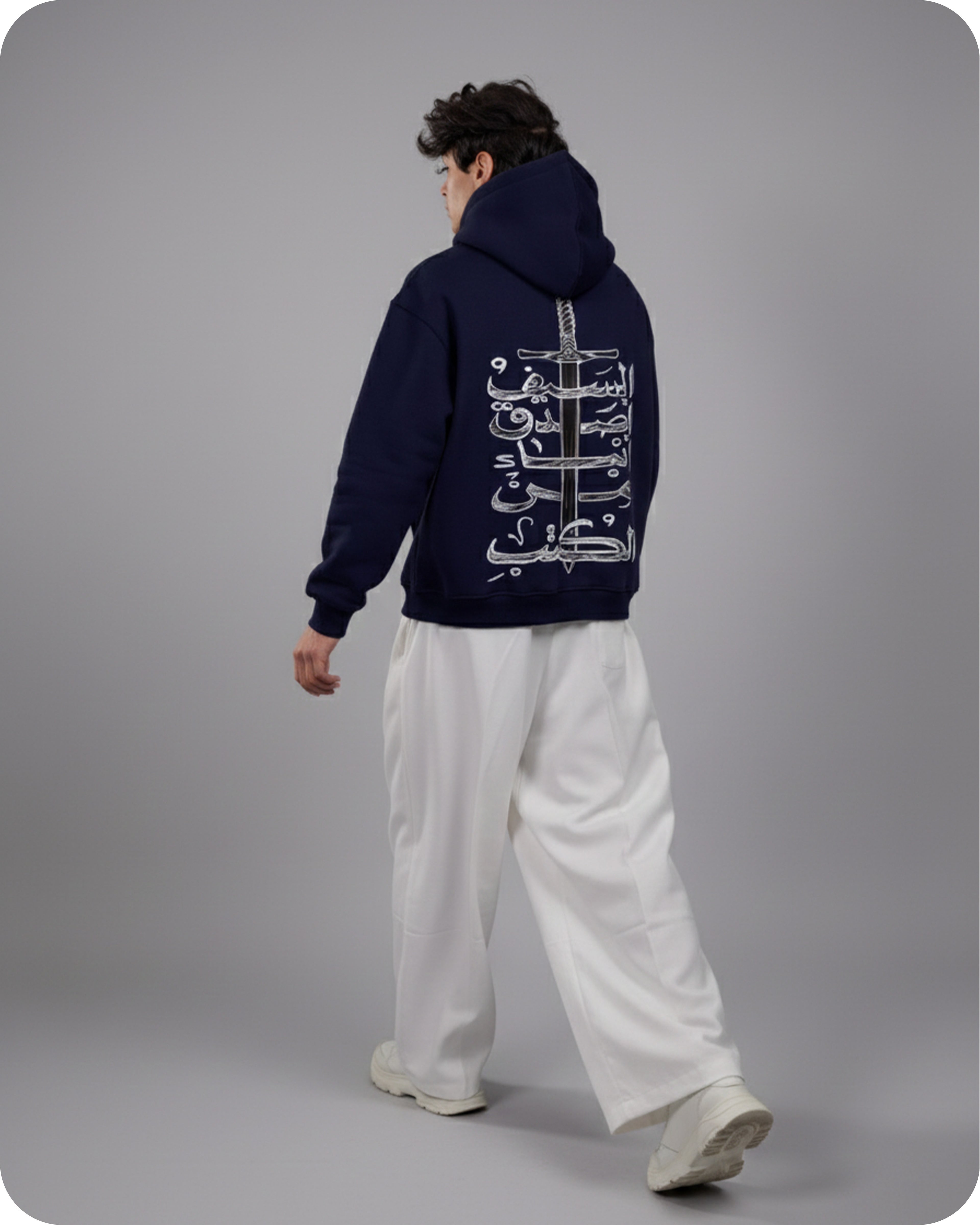 Person wearing a navy hoodie with white text on the back, standing against a gray background