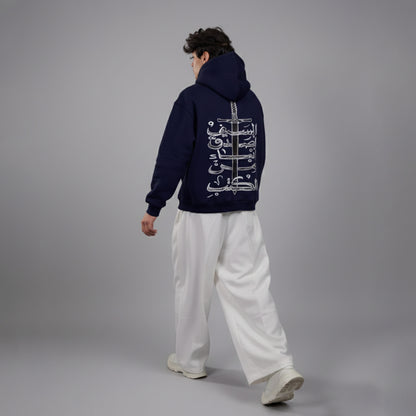 Person wearing a navy hoodie with white text on the back, standing against a gray background