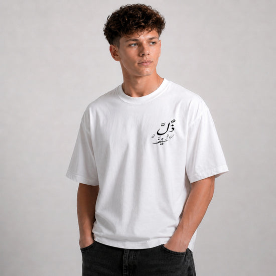 Person wearing a white t-shirt with Arabic text on a plain background