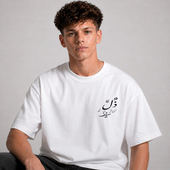 Person wearing a white t-shirt with Arabic text on a plain background
