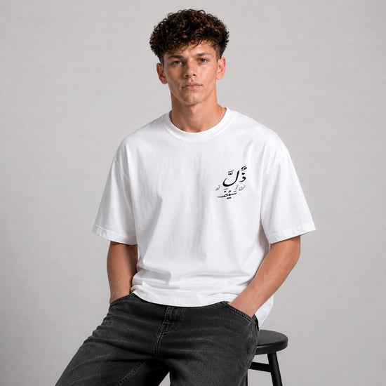 Person wearing a white t-shirt with Arabic text on a gray background