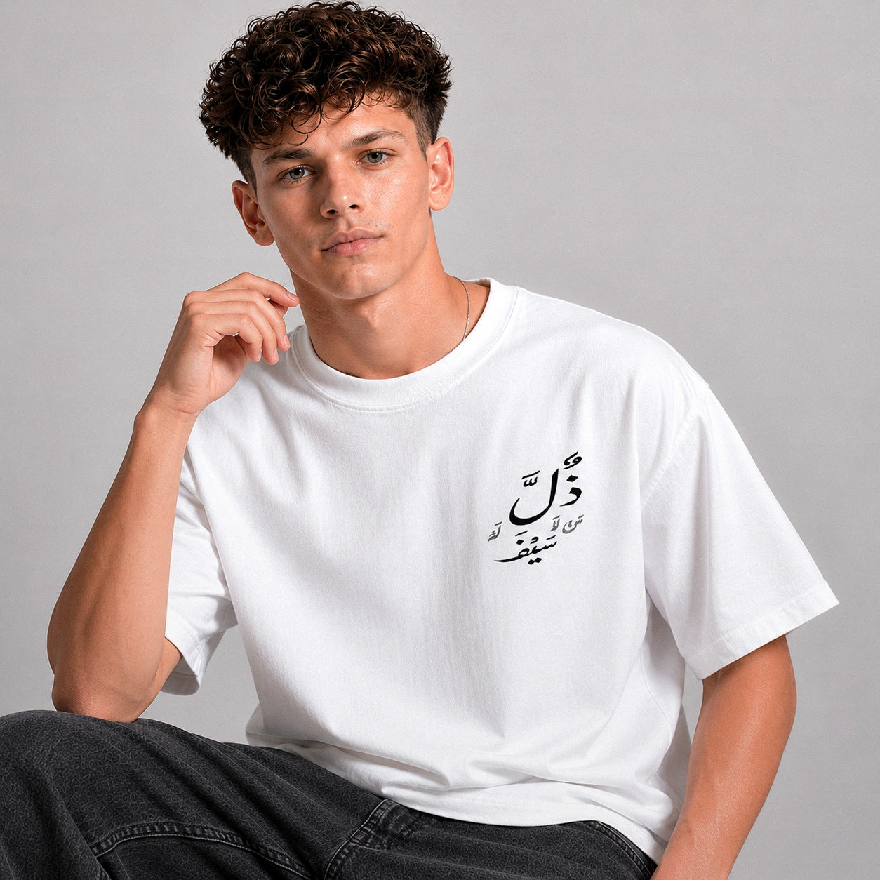 Person wearing a white t-shirt with Arabic text against a gray background