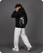 Person wearing a black hoodie with a graphic design on the back against a gray background