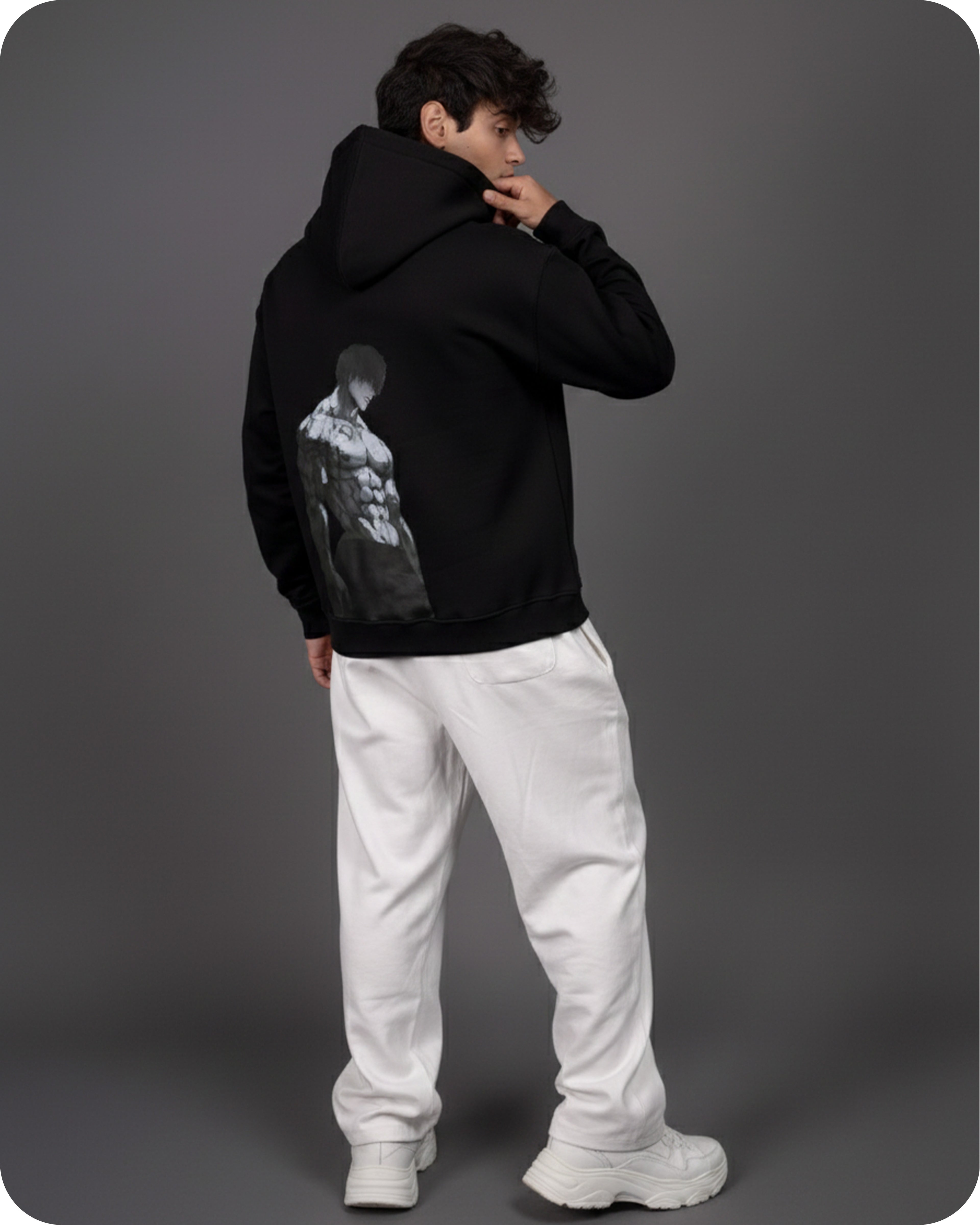 Person wearing a black hoodie with a graphic design on the back against a gray background