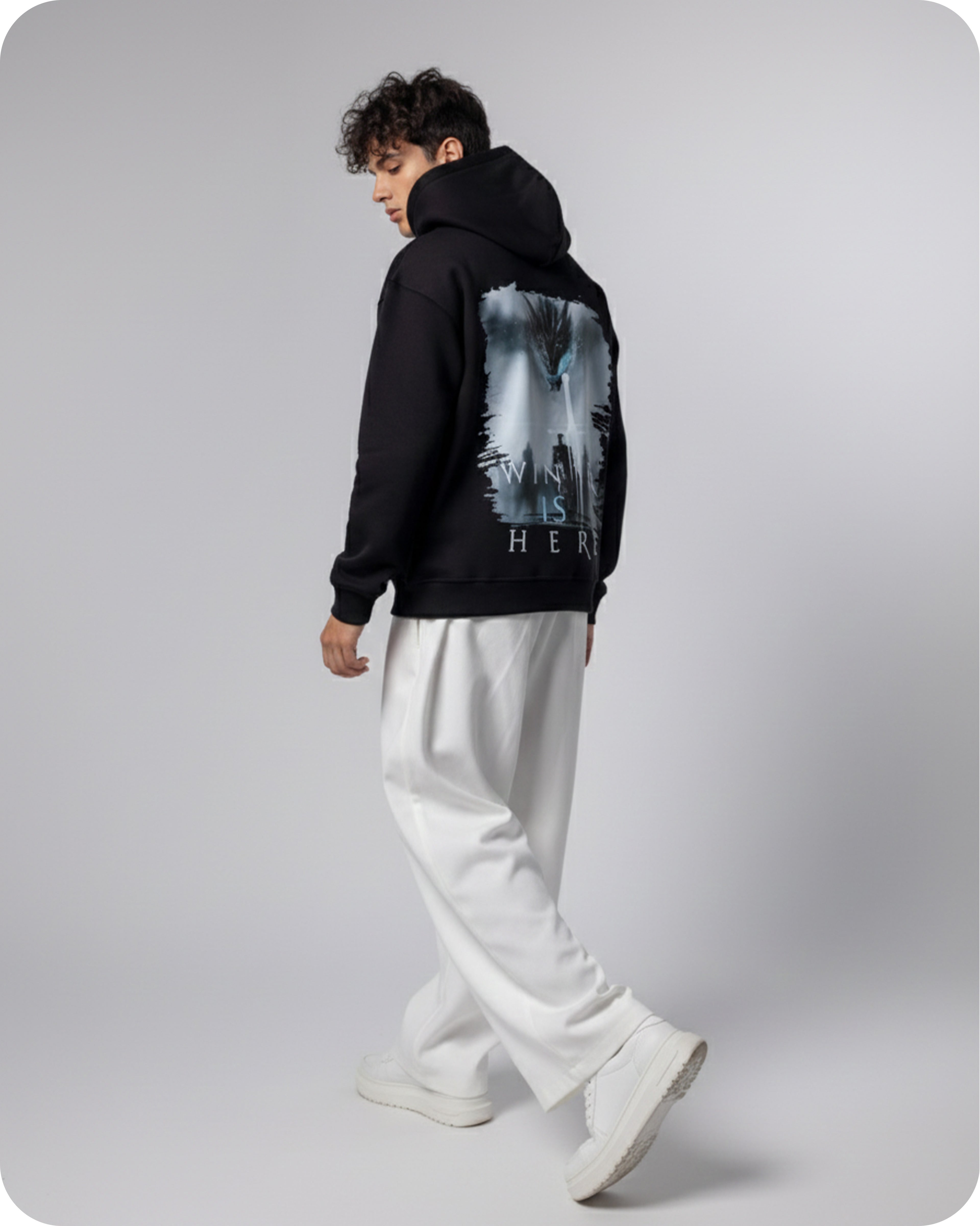 Person wearing a black hoodie with a graphic design on the back, standing against a plain background