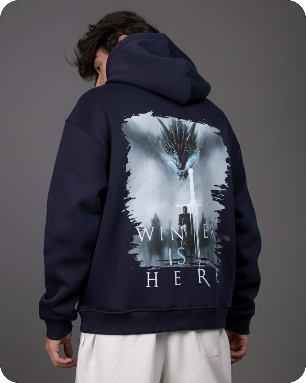 Person wearing a navy hoodie with a graphic design on the back against a gray background