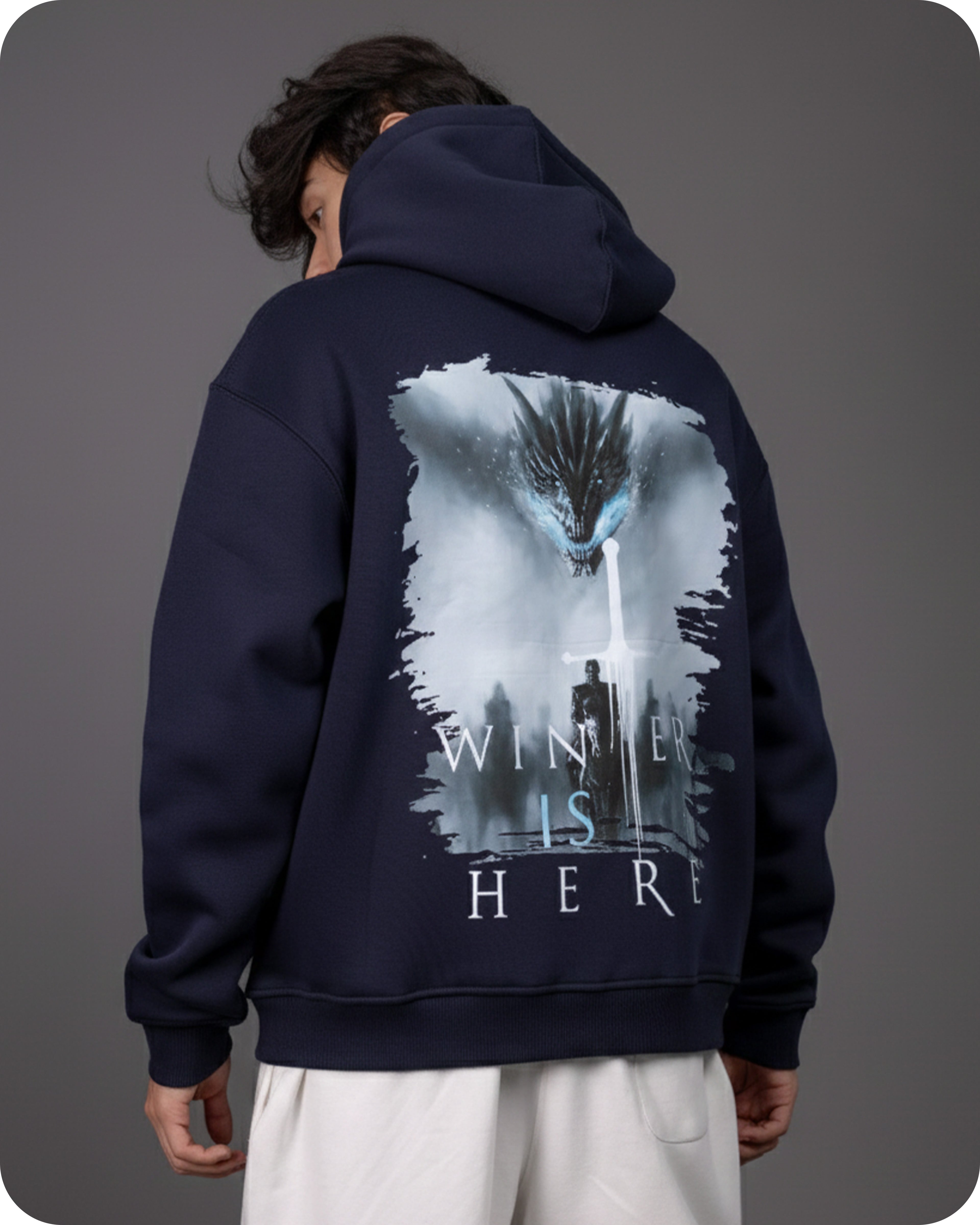 Person wearing a navy hoodie with a graphic design on the back against a gray background