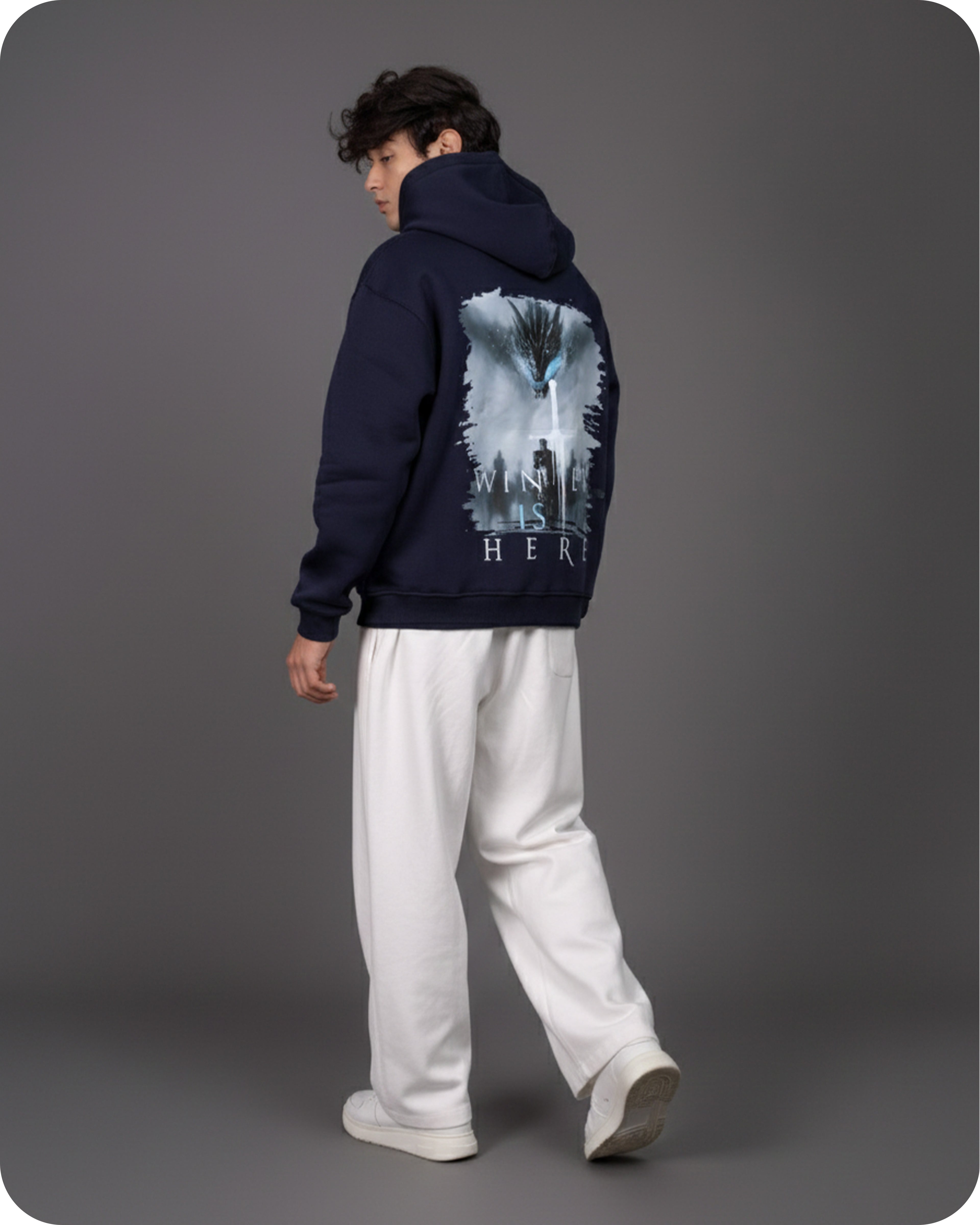 Person wearing a navy hoodie with a graphic design on the back against a gray background