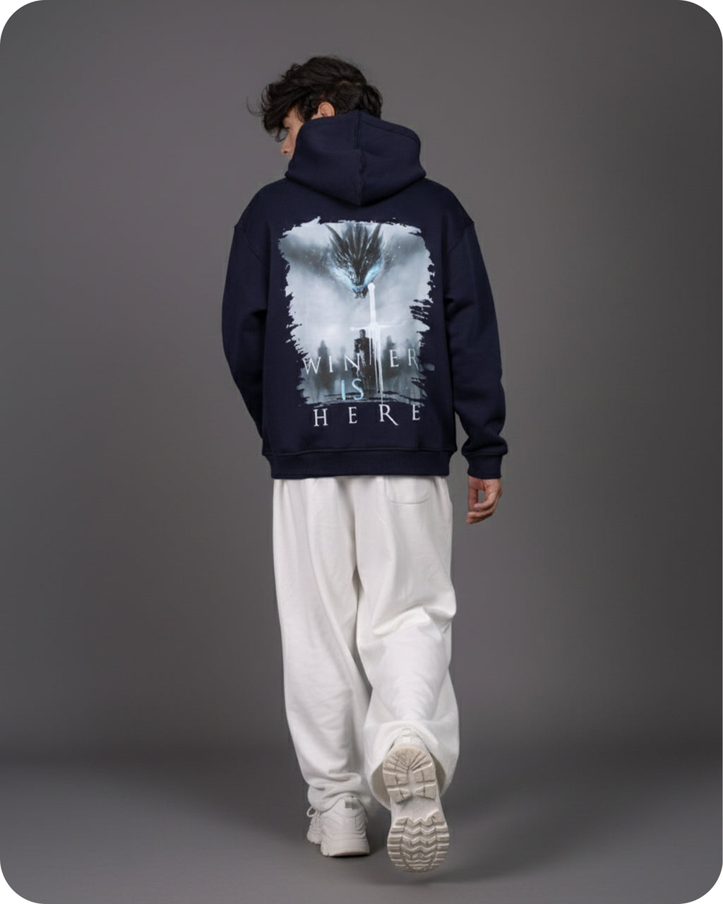 Person wearing a navy hoodie with a graphic design on the back against a gray background